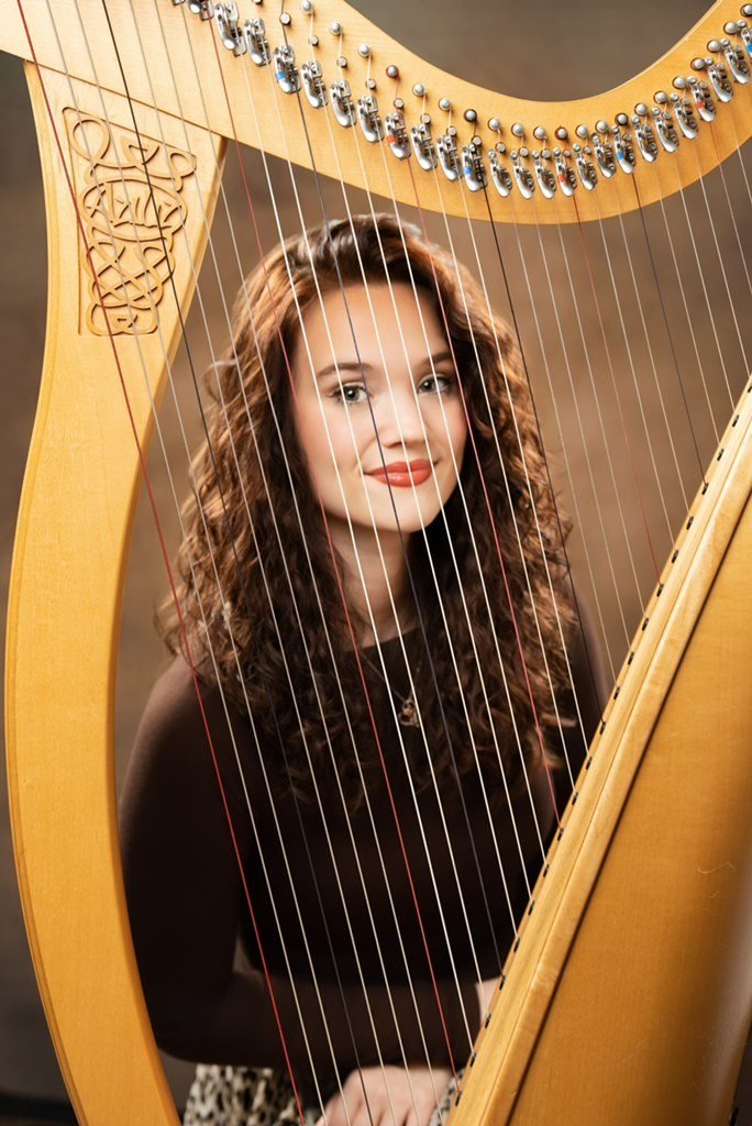 Georgia Pearl seated beside her lever harp
