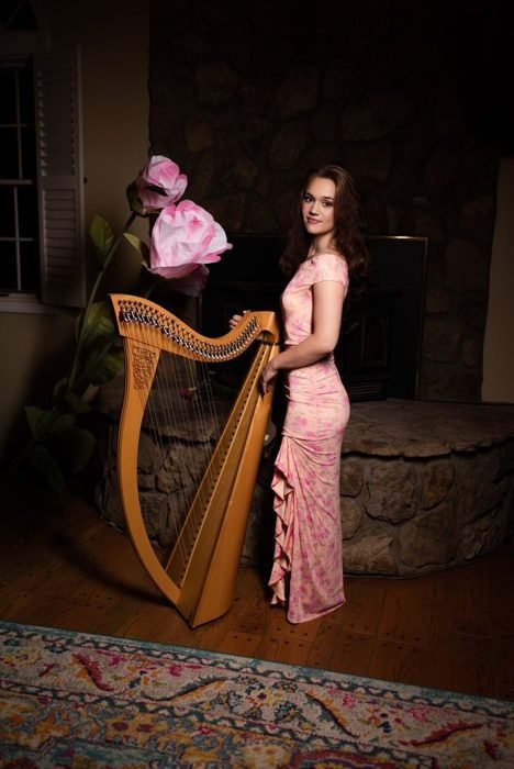 Standing beside the harp in a pink gown